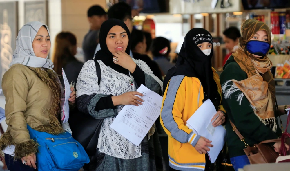 Overseas Filipino Workers hold their documents as they queue upon their arrival at the Ninoy Aquino International Airport, in Metro Manila, Philippines. (REUTERS)