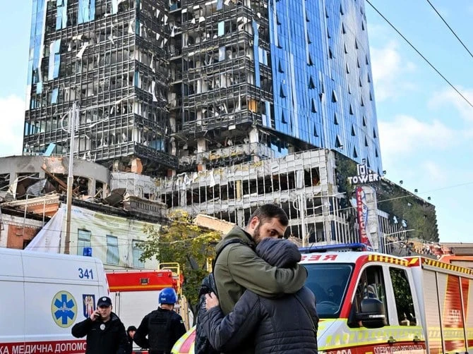 People react outside a partially destroyed multi-storey office building after several Russian strikes hit the Ukrainian capital of Kyiv on October 10, 2022. (AFP/File)