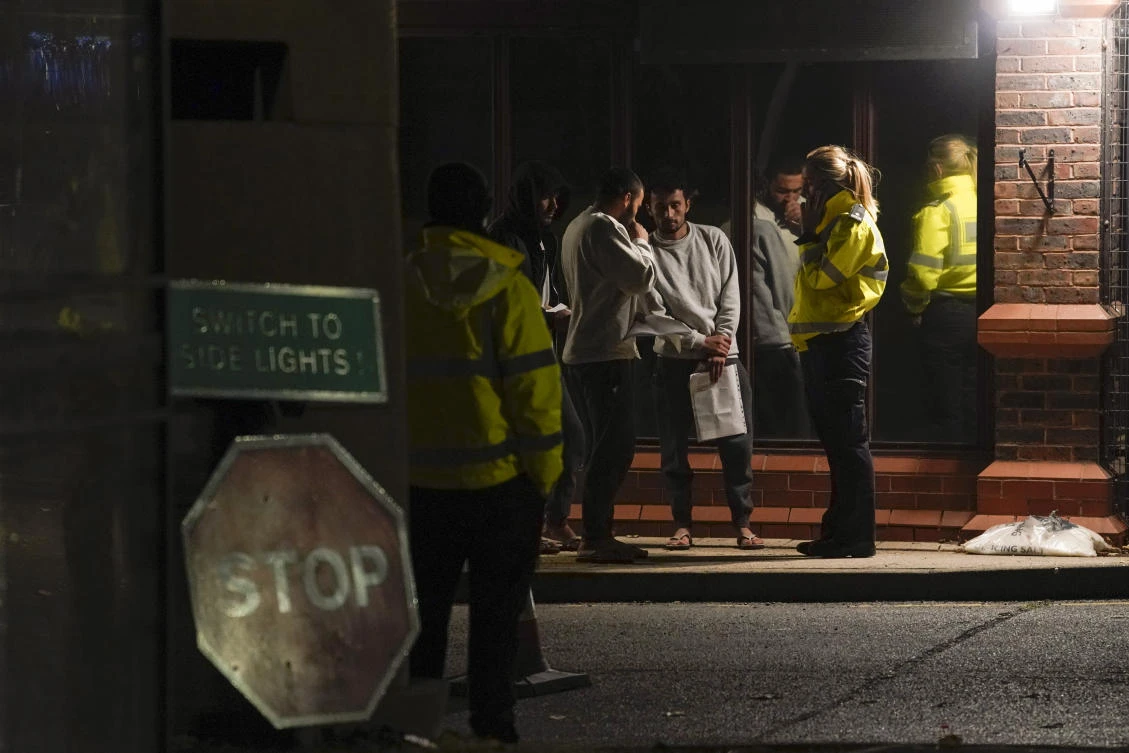 People thought to be migrants talk to the police outside the Manston immigration short-term holding facility near Thanet, Kent, England, Wednesday, Nov. 2, 2022. (File/AP)