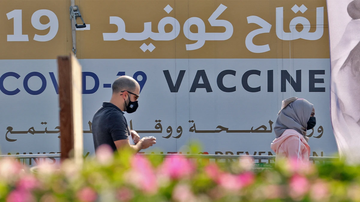 A man and a woman walk past a huge health ministry COVID-19 vaccines announcement outside a medical centre in Dubai, UAE, on February 16, 2021. (AFP/File)