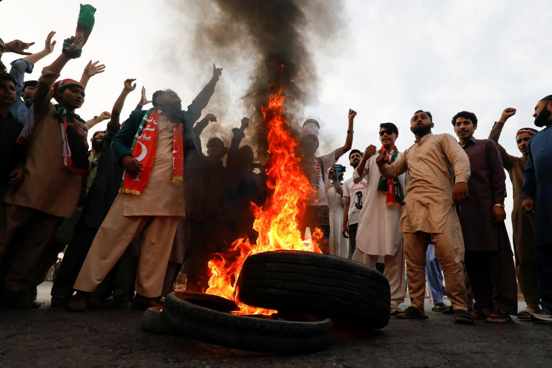 People chant slogans as they burn tires to block main highway during a protest to condemn the shooting incident on a long march held by Pakistan’s former PM Imran Khan, in Wazirabad, on November 4, 2022. (Reuters)