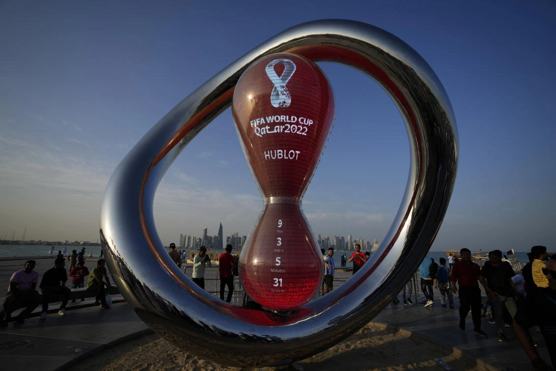 People gather around the official countdown clock showing remaining time until the kick-off of the World Cup 2022, in Doha, on Friday. (AP)