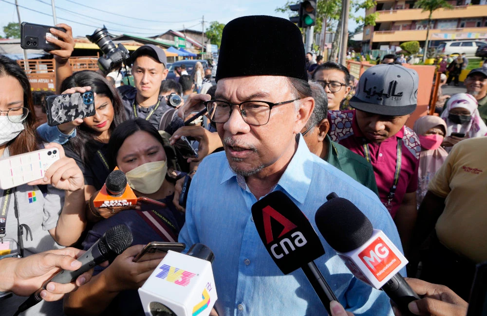 Malaysian opposition leader Anwar Ibrahim is mobbed by the media after casting his vote at a polling station in Seberang Perai, Penang state, Malaysia, Saturday, Nov. 19, 2022. (AP)