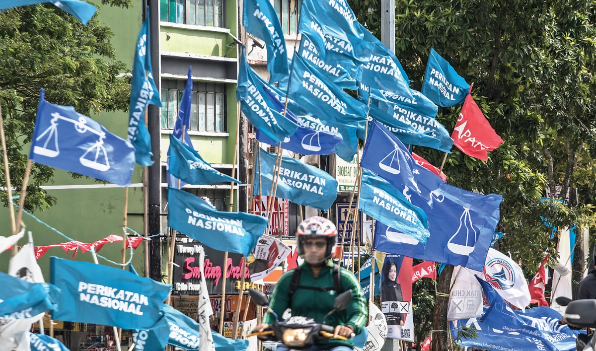 Motorcycles pass campaign flags of Malaysia’s ruling National Front coalition and Pakatan Harapan displayed in Kuala Lumpur on Sunday. (AP)