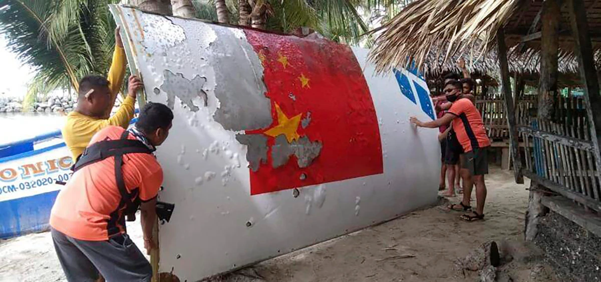 Philippine Coast Guard personnel carry debris with markings of a Chinese rocket that was launched on July 24, after it was found in waters in the central Philippines on Aug. 2022. (AP file)
