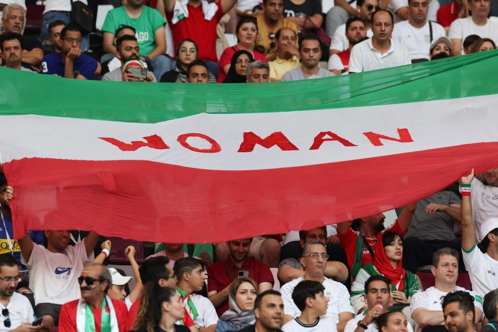 Iranian supporters display a national flag with the word ‘Woman’ during the Qatar 2022 World Cup match against England, Khalifa International Stadium, Doha, Nov. 21, 2022. (AFP)