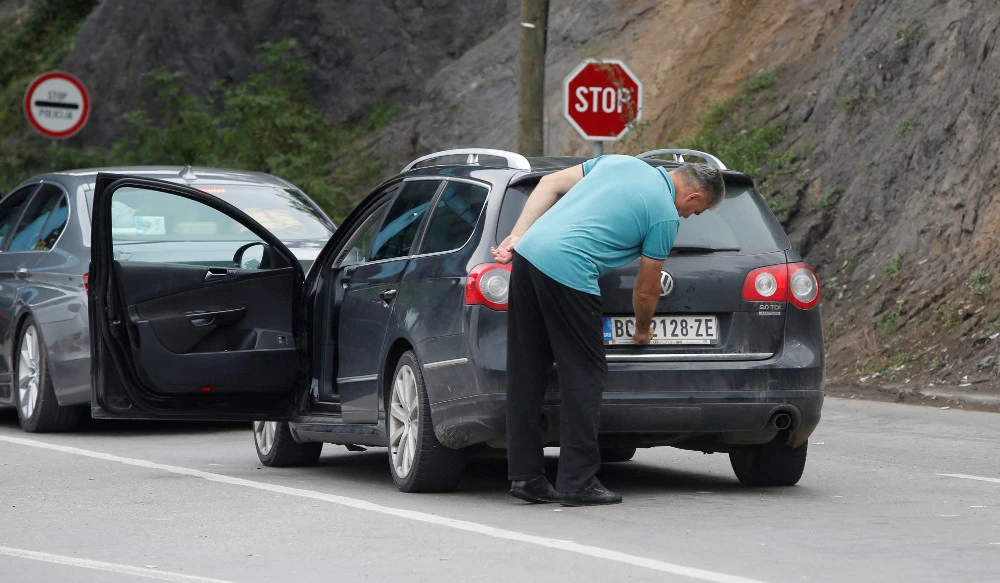 A driver removes a sticker covering the national markings on his car plates at the Jarinje border crossing, Kosovo September 1, 2022. (REUTERS)