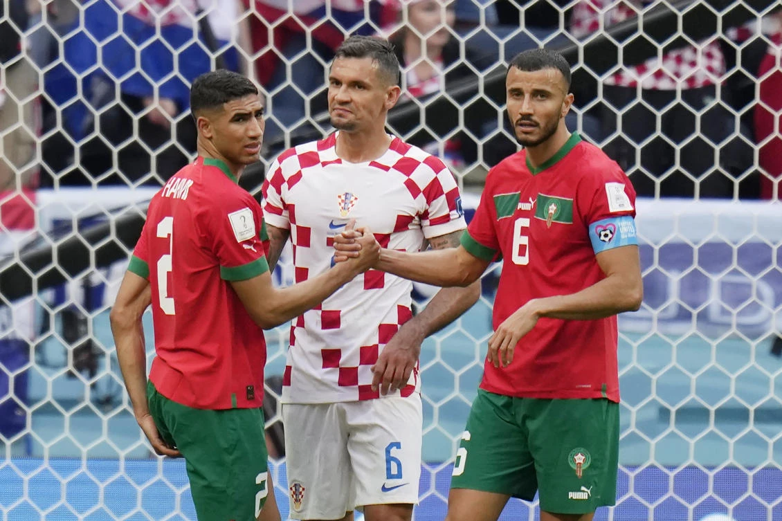 Morocco’s Achraf Hakimi and Romain Saiss shake hands as Croatia’s Dejan Lovren looks on after their World Cup match at the Al Bayt Stadium in Al Khor, on Wednesday. (AP)