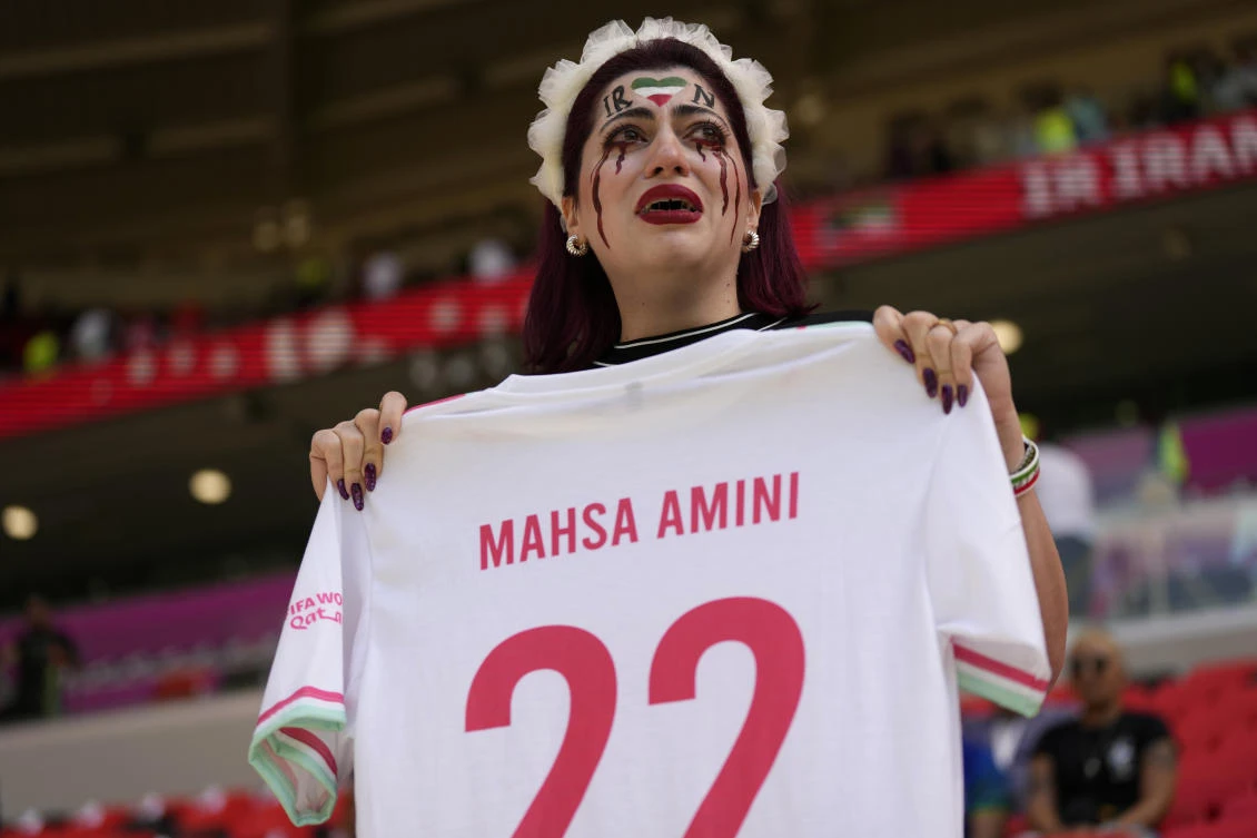 An Iran supporter cries as she holds a shirt which reads 'Mahsa Amini' prior to the start of the World Cup group B soccer match between Wales and Iran in Qatar. (AP)