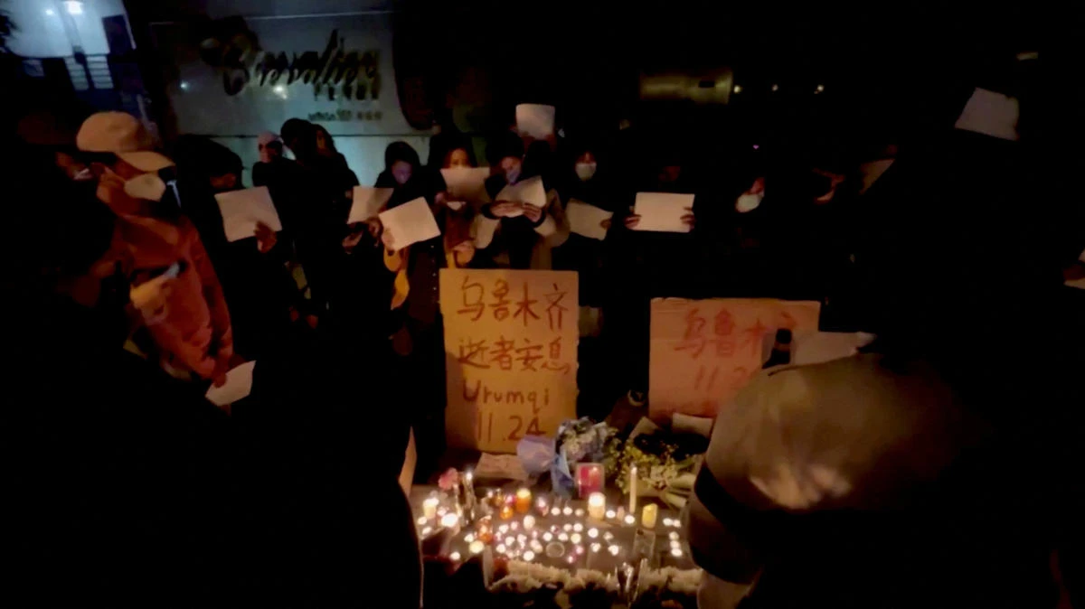People in Shanghai hold signs and light candles during a vigil held for the victims of the Urumqi fire. (Gao Ming via Reuters)