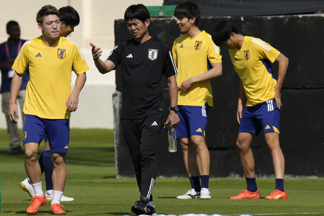 Japan’s head coach Hajjime Moriyasu, center, speaks with Ritsu Doan, left, who will come into the starting line-up against Costa Rica. (AP)