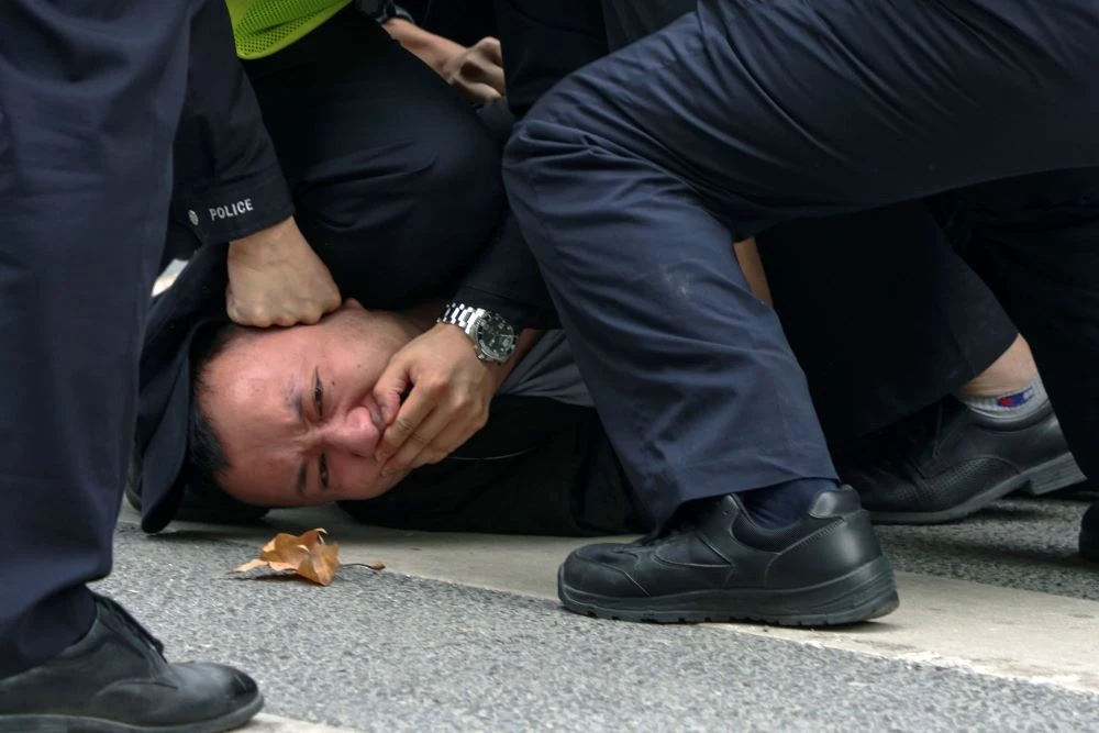 Policemen pin down and arrest a protester during an anti-COVID-19 measures demonstration in Shanghai, China, Sunday, Nov. 27, 2022. (AP Photo)
