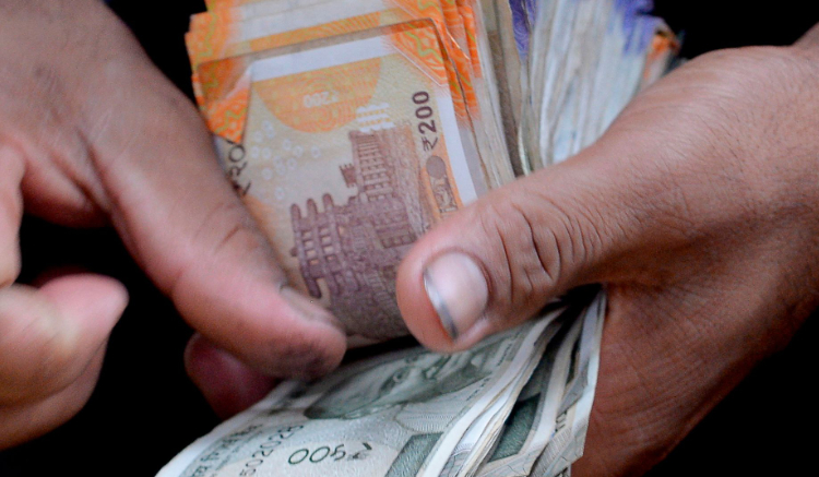 A fruit vendor counts a wad of Indian Rupee currency notes in Mumbai on July 19, 2022. (AFP)