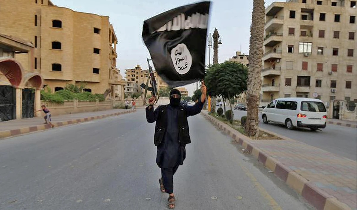 A member loyal to the Islamic State in Iraq and the Levant (ISIL) waves an ISIL flag in Raqqa, Syria on June 29, 2014. (REUTERS/File)