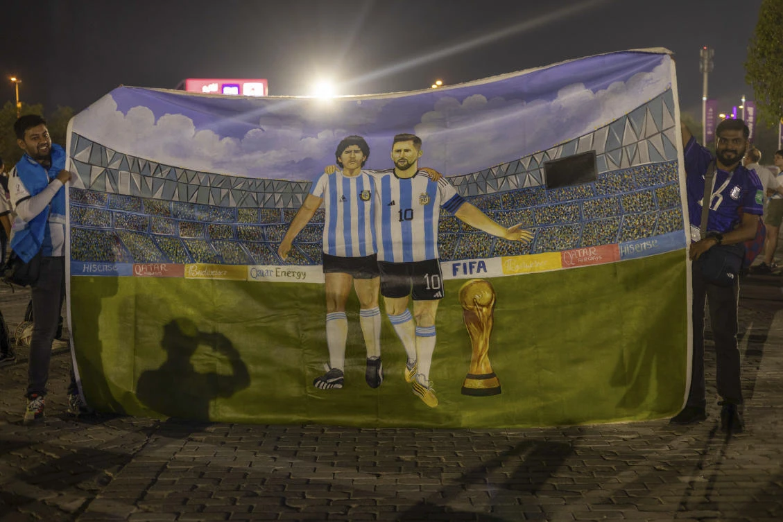 Mohid Data and Aayush Verma from India show a huge painting of their heroes, Lionel Messi and Diego Maradona with the World Cup trophy on Dec. 30, 2022. (AP)