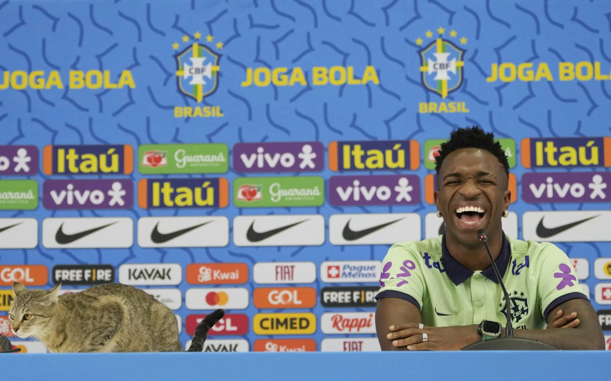 Brazil’s Vinicius Junior smiles as a cat sits on the table during a press conference after a training session at the Grand Hamad stadium in Doha on Wednesday. (AP)