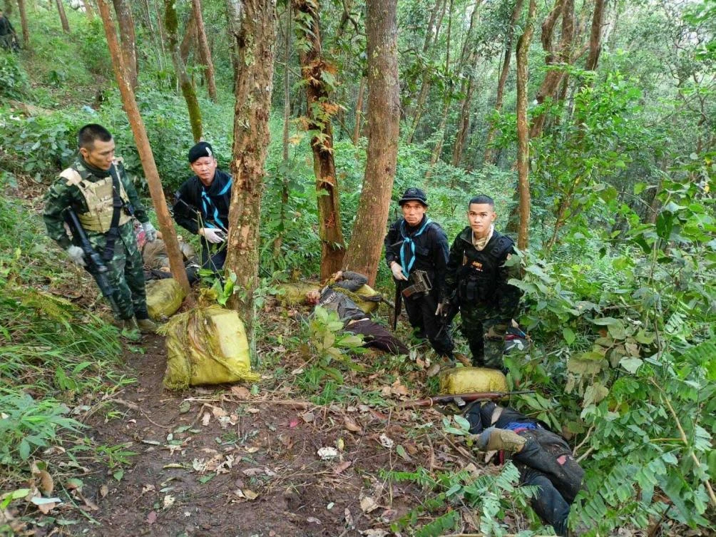 Thai soldiers stand with seized packages of illegal drugs and the body of a suspected smuggler at Fang district in Chiang Mai of northern Thailand. (Pha Muang Force via AP)