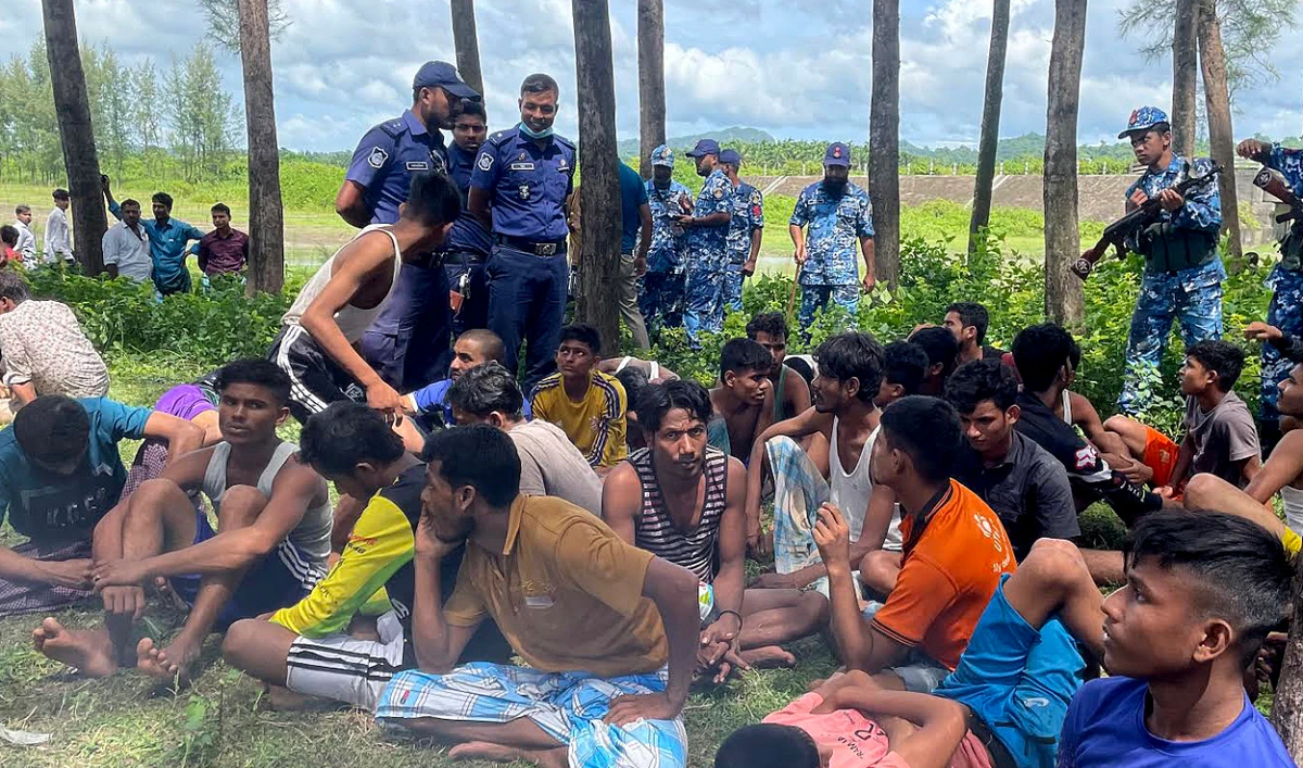 Bangladesh security personnel stand guard beside Rohingya refugees rescued from the sea after a Malaysia bound boat sank off the Bangladesh coast in Teknaf on October 4, 2022. (AFP/File)