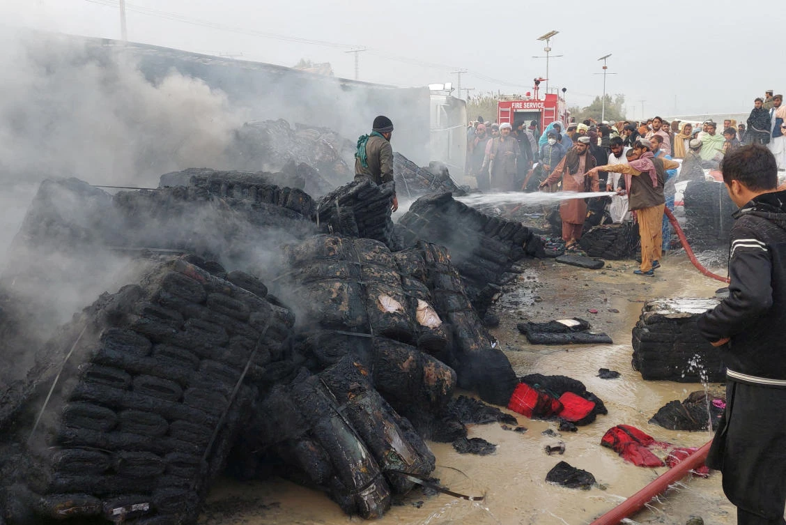 People douse a cargo supply truck after it was hit during the artillery shelling, in the Pakistan-Afghanistan border town of Chaman on Dec. 11, 2022. (Reuters)