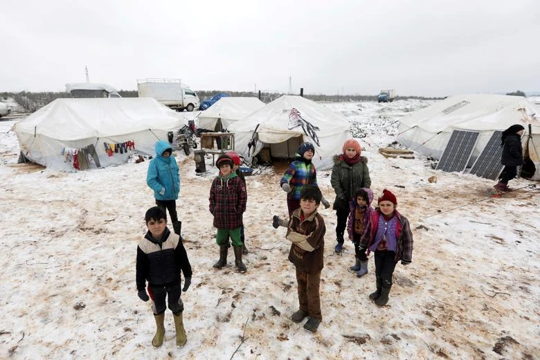 Internally displaced children stand on snow near tents at a makeshift camp in Azaz, Syria. (Reuters)