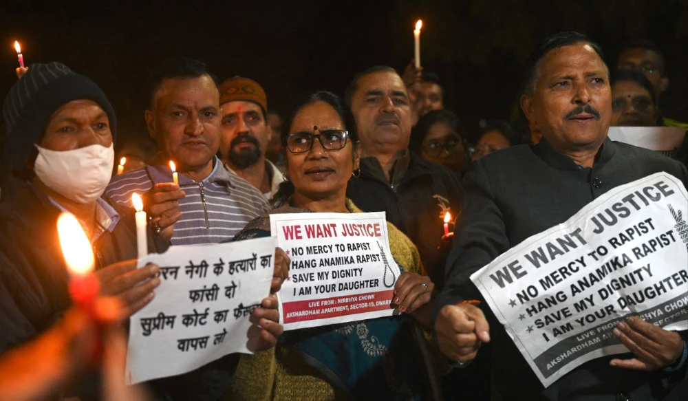 Asha Devi (C), mother of the 2012 Delhi gang rape victim, along with people hold candles and placards during a vigil on the tenth anniversary of the heinous gang rape of a young woman in New Delhi on December 16, 2022. (AFP)