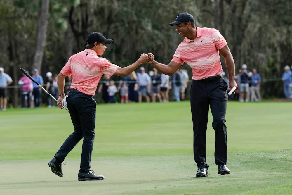 Tiger Woods, right, and his son Charlie bump fists on the ninth green during the first round of the PNC Championship golf tournament Saturday in Orlando, Florida. (AP)