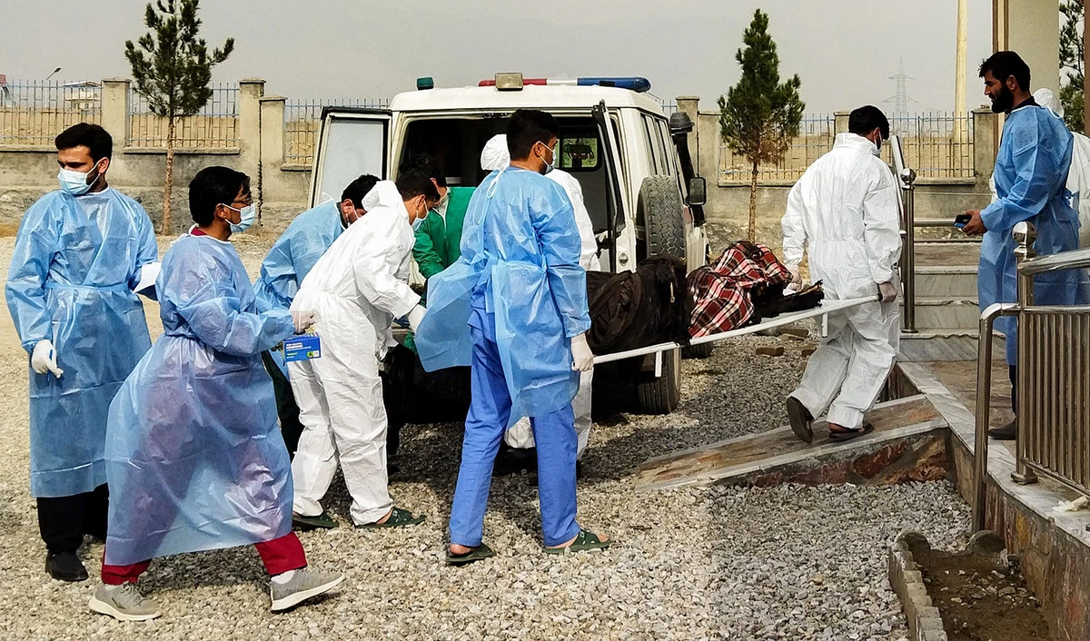 Afghan medical staff carry the bodies of the victims who lost their lives after an oil tanker caught fire a night before at Salang pass tunnel in Charikar, Afghanistan on December 18, 2022. (AFP)