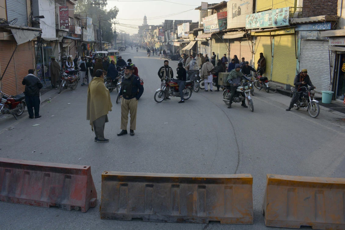 Police stand guard along a road they blocked after Taliban militants seized a police station in Bannu, Pakistan, on December 19, 2022. (AP)