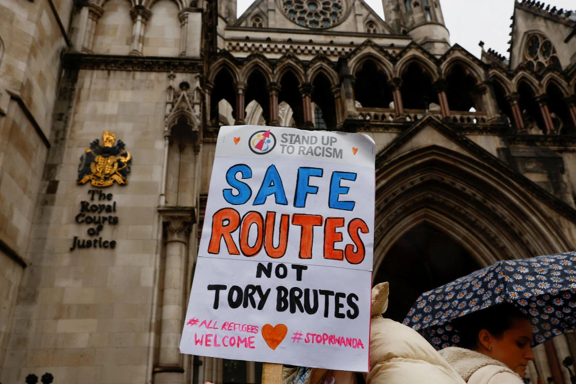 A protestor holds a placard while demonstrating against the government's policy to deport illegal immigrants to Rwanda in London. (Reuters)