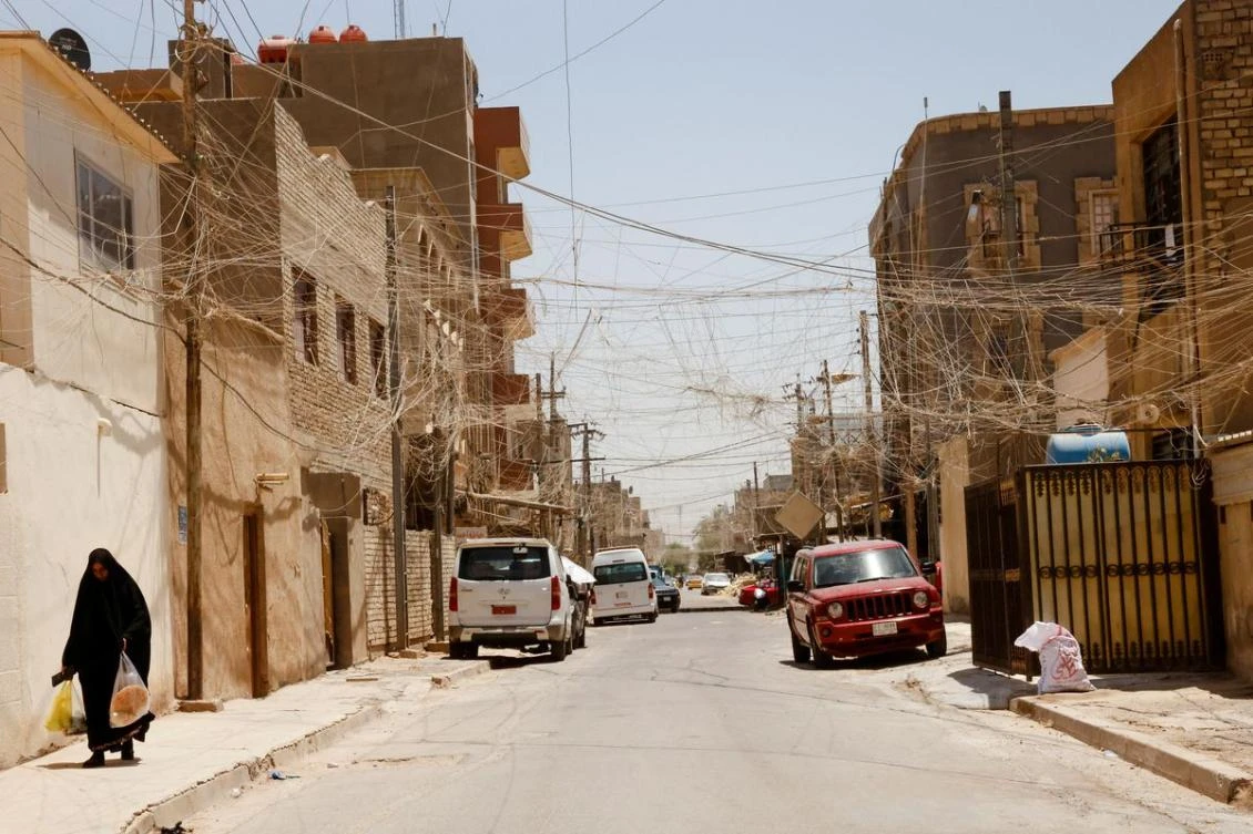 An Iraqi woman walks along a street in Baghdad, Iraq, July 20, 2022. (Reuters)