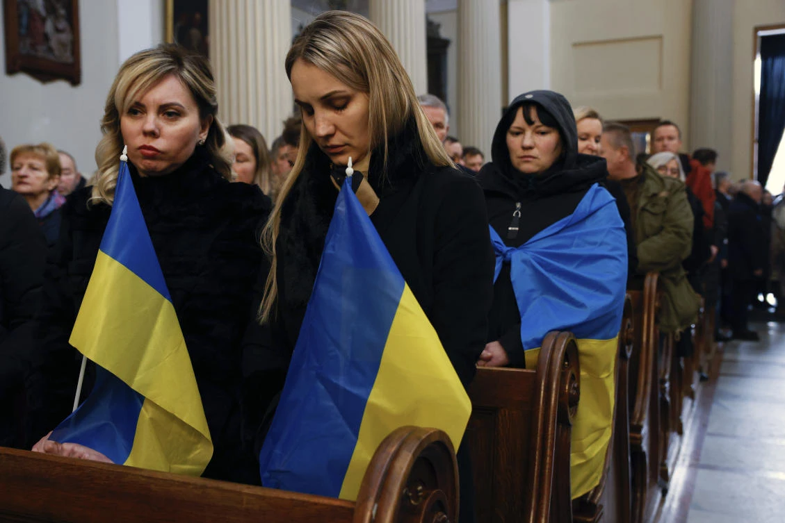 Women holding Ukrainian flags attend the funeral ceremony of Daniel Sztyber, a 35-year-old man from Warsaw who died fighting in Ukraine, in the Church of St. Andrew the Apostle in Warsaw on Dec. 20, 2022. (AP)