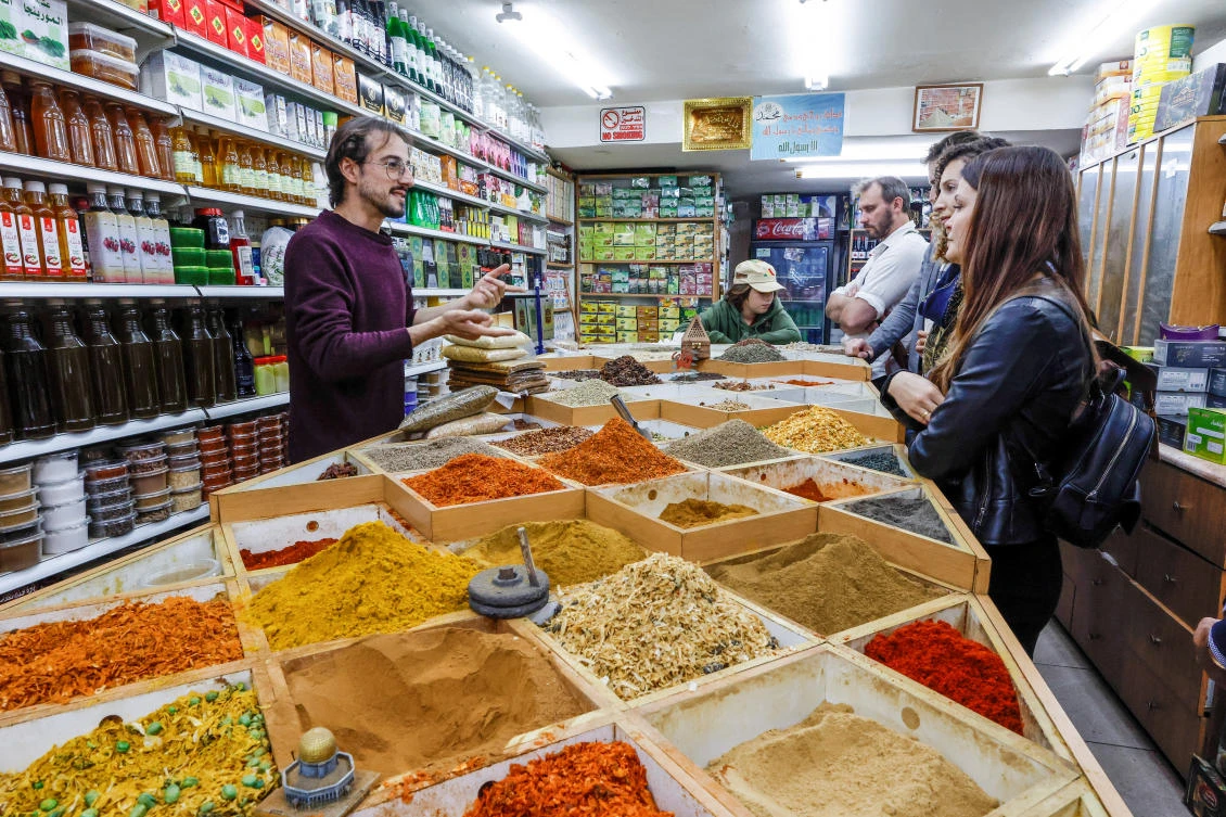 Izzeldin Abdul Aziz Bukhari, founder of SacredCuisine, guides a group of tourists in a spice shop at a market in Jerusalem’s Old City, on December 11, 2022. (Reuters)