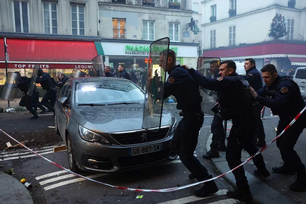 French riot police run to disperse protesters during a clash after three people were killed in a shooting in Paris on Dec. 23, 2022, (AFP)