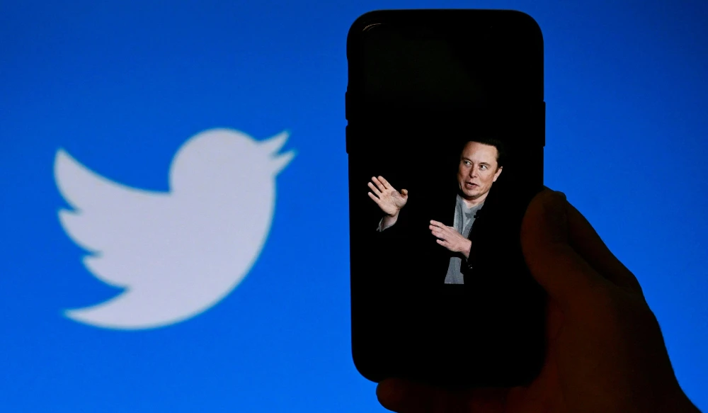 In this file photo taken on October 4, 2022, a phone screen displays a photo of Elon Musk with the Twitter logo shown in the background, in Washington, DC. (AFP)