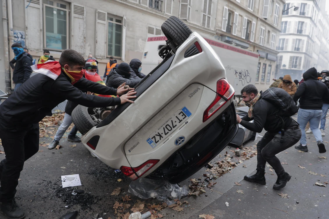Demonstrators turn a car over during a protest against the recent shooting at the Kurdish culture center in Paris (AP)