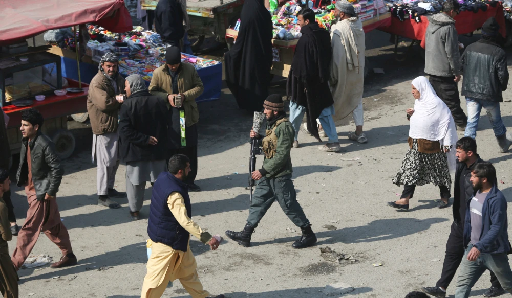 A security police officer, center, walks through a busy bazaar in Kabul, Afghanistan. (AP)
