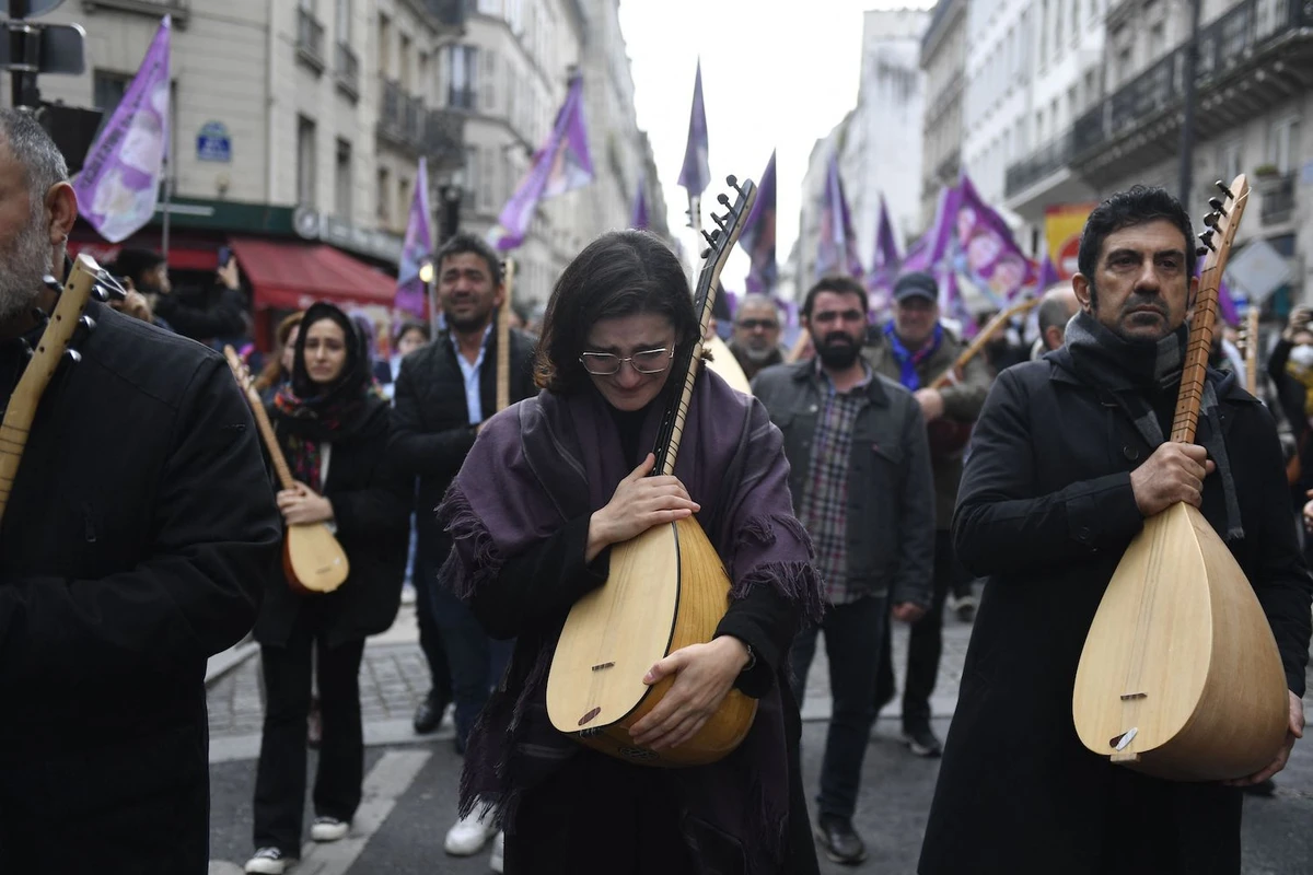 Protesters react as they hold Kurdish traditional musical instruments while taking part in a demonstration to pay tribute to the Enghien Street shooting victims in Paris. (AFP)