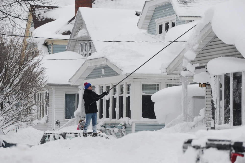 A man attempts to clear his roof of snow on December 26, 2022 in Buffalo, New York. (AFP)