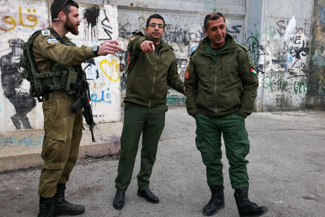 An Israeli soldier (L) chats with Palestinian security force members in the occupied West Bank town of Bethlehem on December 24, 2022. (File/AFP)
