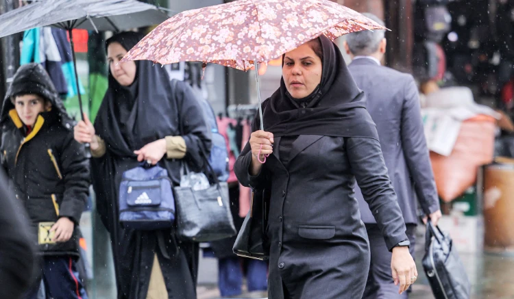 A woman walks with an umbrella at Enghelab Square in Iran's capital Tehran on December 5, 2022. (AFP)