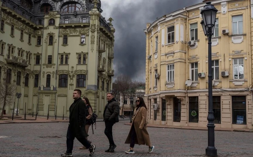 People walk in a street as smoke rises in the air after shelling in Odesa, Ukraine, April 3, 2022. (AP Photo)