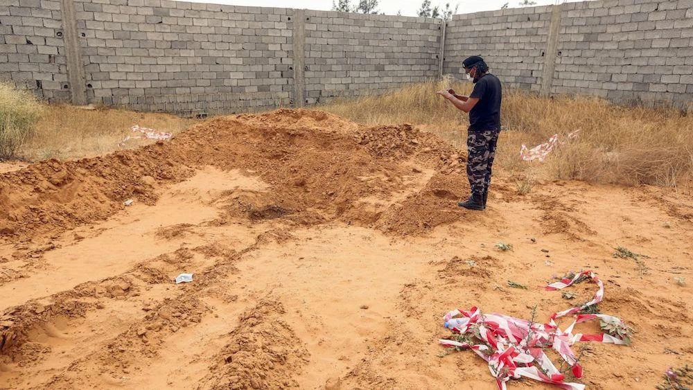 A member of security forces affiliated with the Libyan Government of National Accord (GNA)'s Interior Ministry takes a picture as he stands at the reported site of a mass grave in 2020. (AFP/File Photo)
