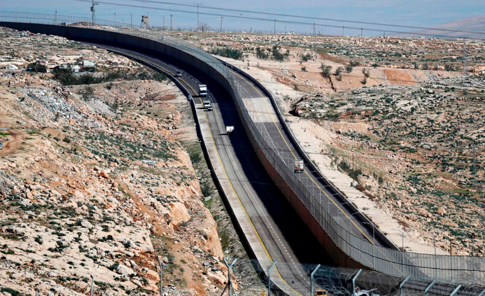 Cars drive on a new Israeli road divided by a wall to separate it for Palestinians (L) and the side to be used exclusively by Israelis and settlers (R) in East Jerusalem, on January 10, 2019. (AFP)