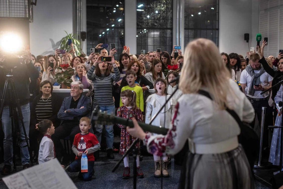 Participants are seen singing carols with Ukrainian singer Mariya Burmaka during the Christmas supper for Ukraininan refugees staying in Warsaw on Orthodox Christmas Eve in Warsaw on January 6, 2023. (AFP)