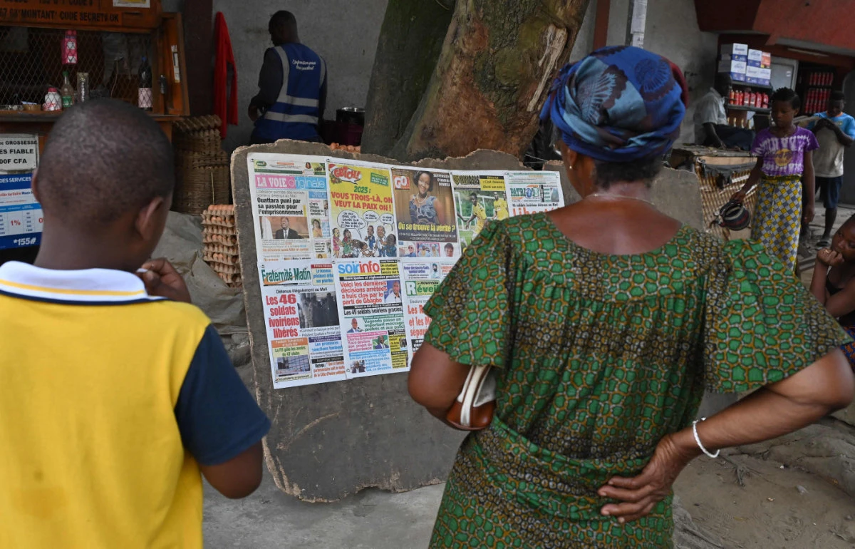 Local residents read the headlines of local newspapers in Abidjan announcing the release of 46 Ivorian soldiers arrested in July 2022 in Mali. (AFP)