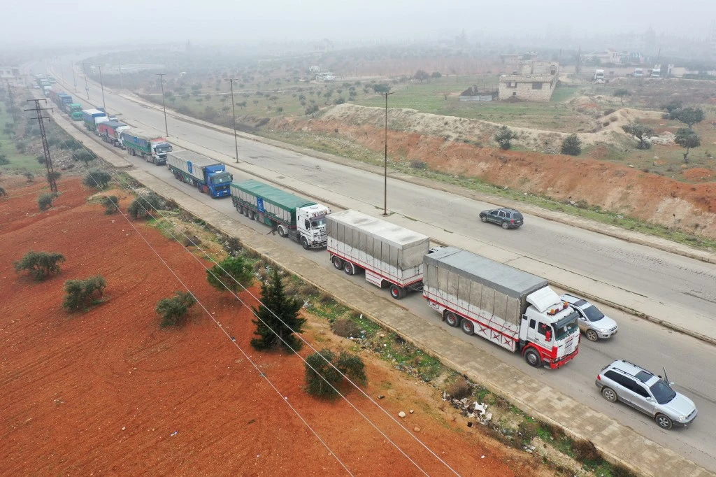 An aerial view shows trucks carrying aid packages from the World Food Program driving through Syria’s rebel-held northwestern city of Idlib on January 8, 2023. (AFP)