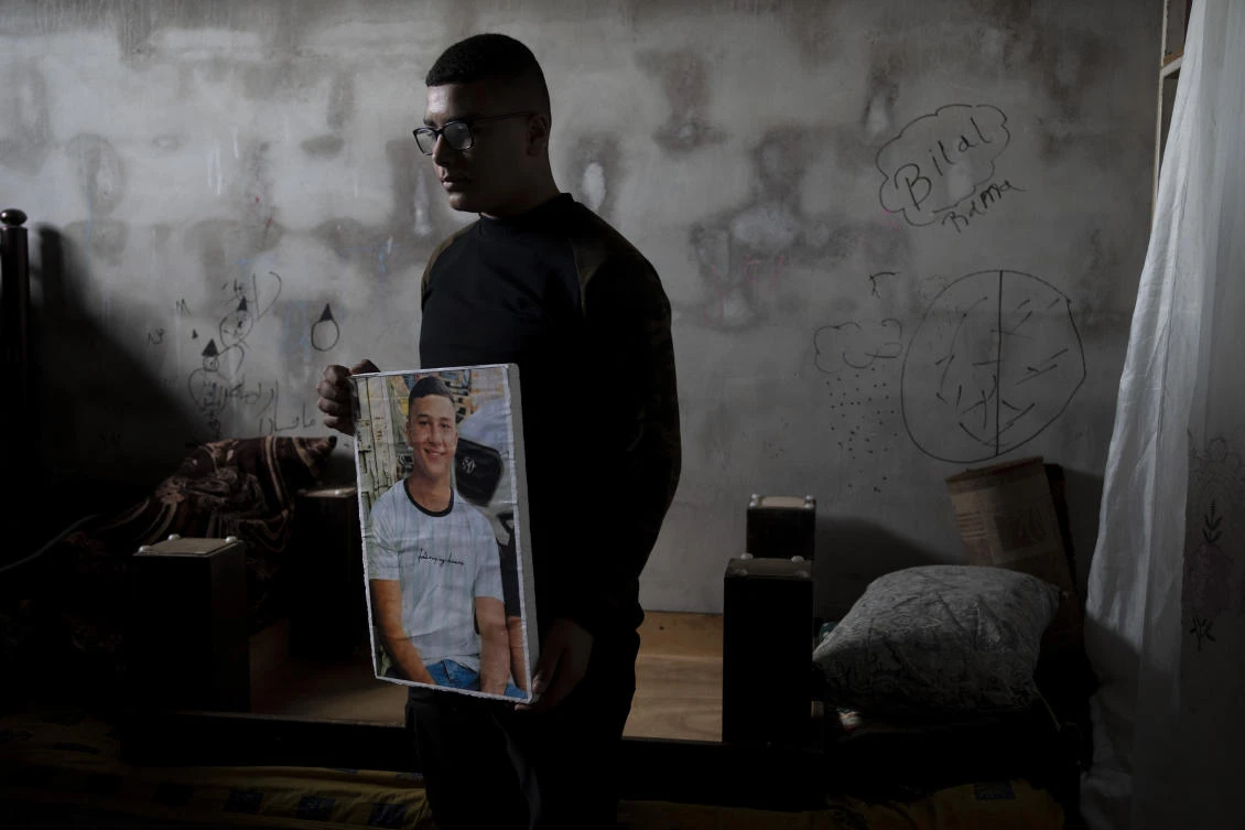 Yousef Mesheh, 15, holds a portrait of his brother, Wael in the bedroom where Israeli forces stormed into their home at 3.a.m., in the Balata Refugee Camp and arrested them both. Wael is still imprisoned. (AP)