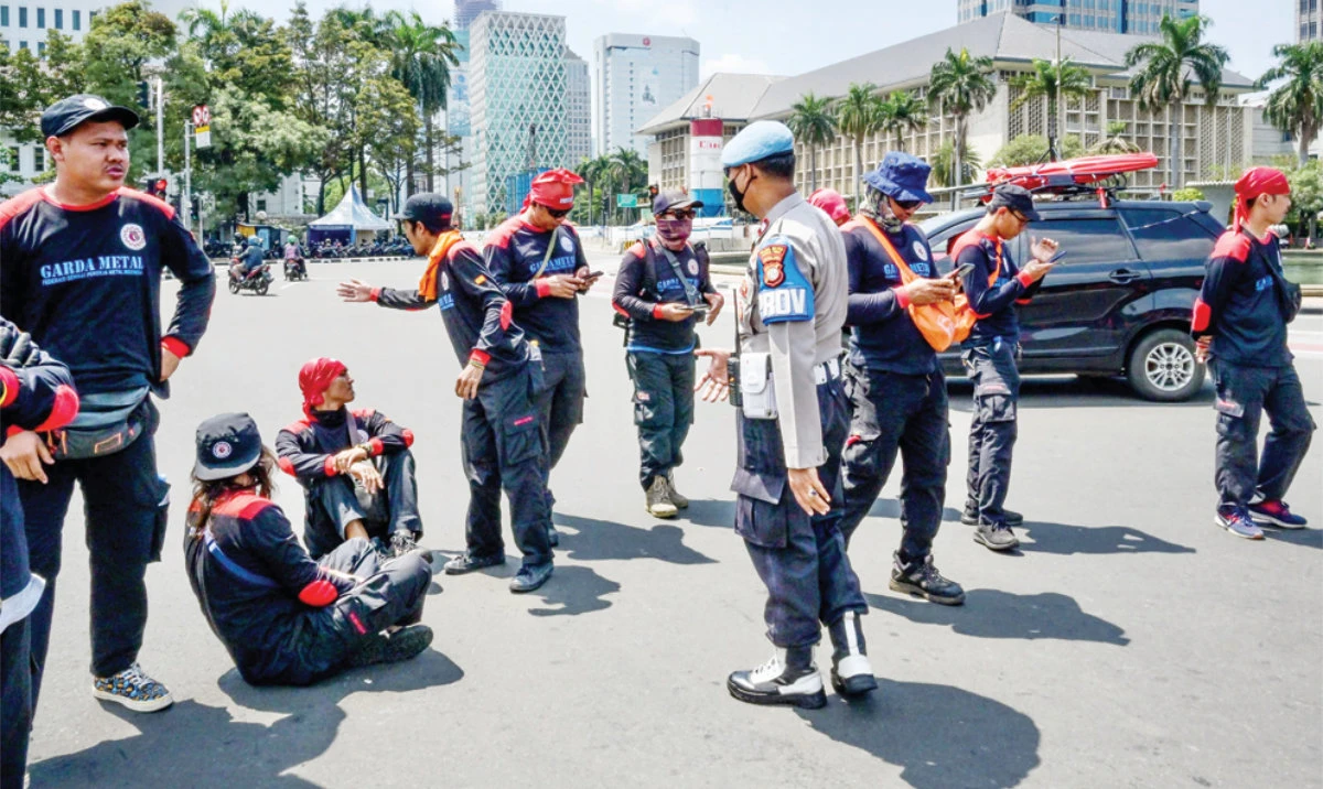 A police officer orders workers to step away from the road during a rally to protest against the job creation bill which they deemed only profits business in Jakarta, Indonesia, on Saturday. (AFP)