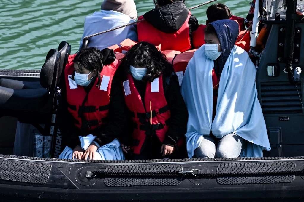 Migrants are seen on the UK Border Force rubber dinghy, after they were picked up at sea while attempting to cross the English Channel, and brought to the Marina in Dover (AFP)