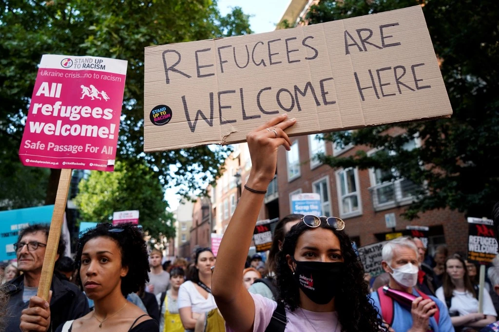 Protesters hold placards as they gather outside the Home Office in central London on June 13, 2022, to demonstrate against the UK government's intention to deport asylum-seekers to Rwanda (AFP)